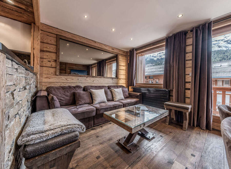 Experience luxurious mountain living in this stunning chalet-style living room, featuring a plush sectional sofa and a unique glass-top coffee table.