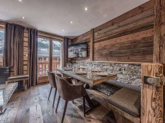 Experience rustic charm and modern comfort in this dining area, featuring a stunning glass-top table with a live-edge wood base, complemented by plush upholstered chairs and a built-in banquette.