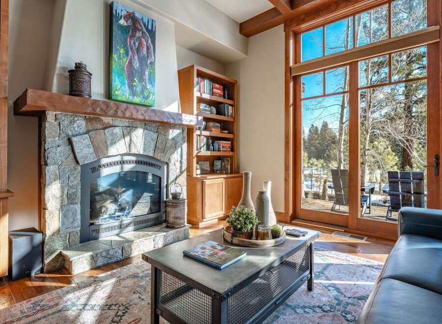 Experience the warmth of this stunning living room, featuring a cozy stone fireplace and a beautiful wooden bookshelf.
