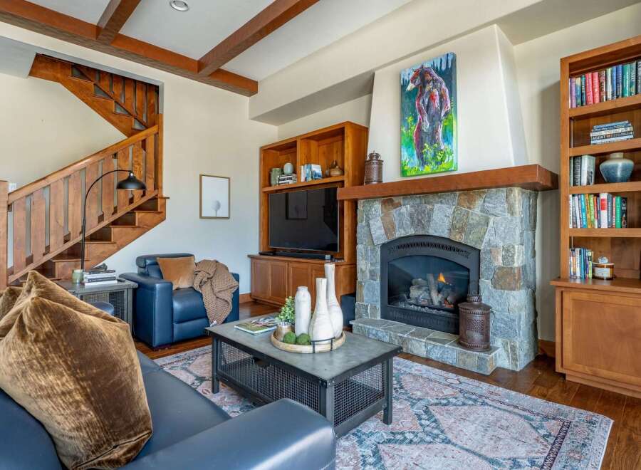 Step into luxury with this stunning living room, featuring a cozy fireplace and a beautiful wooden staircase.