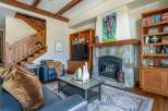 Step into luxury with this stunning living room, featuring a cozy fireplace and a beautiful wooden staircase.
