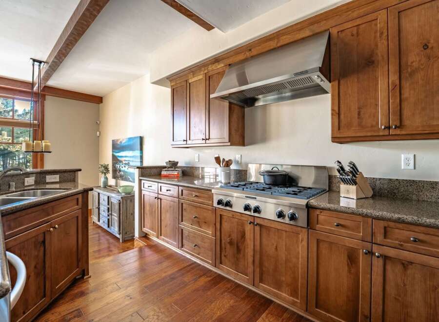 This stunning kitchen boasts beautiful wooden cabinetry and a stainless steel range hood, creating a warm and inviting atmosphere.