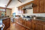 This stunning kitchen boasts beautiful wooden cabinetry and a stainless steel range hood, creating a warm and inviting atmosphere.