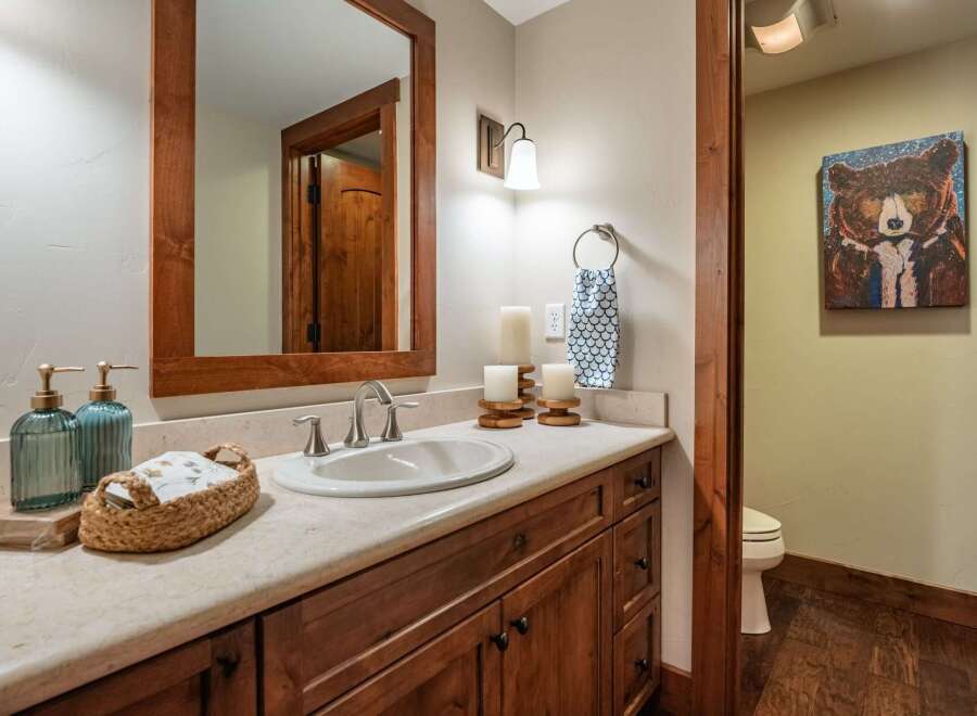 This charming bathroom features a warm, inviting ambiance with its wooden cabinetry and a large mirror.