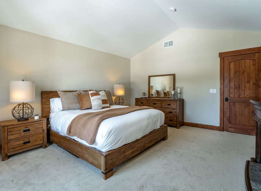 Step into a serene bedroom retreat, featuring a spacious bed with plush bedding and decorative pillows.