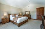 Step into a serene bedroom retreat, featuring a spacious bed with plush bedding and decorative pillows.