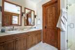 This stunning bathroom features a beautiful wooden vanity with dual sinks, offering ample space and storage.