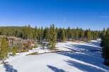 Discover a stunning property nestled in a winter wonderland, surrounded by towering pine trees and pristine snow.
