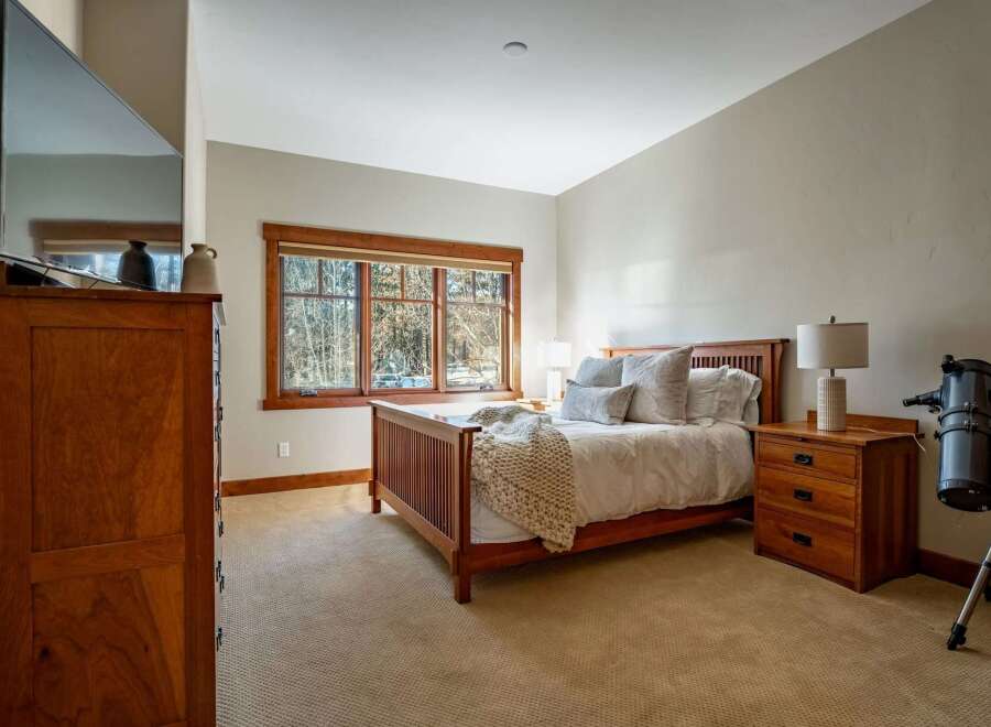 This inviting bedroom features a cozy ambiance with a wooden bed frame and matching nightstands.