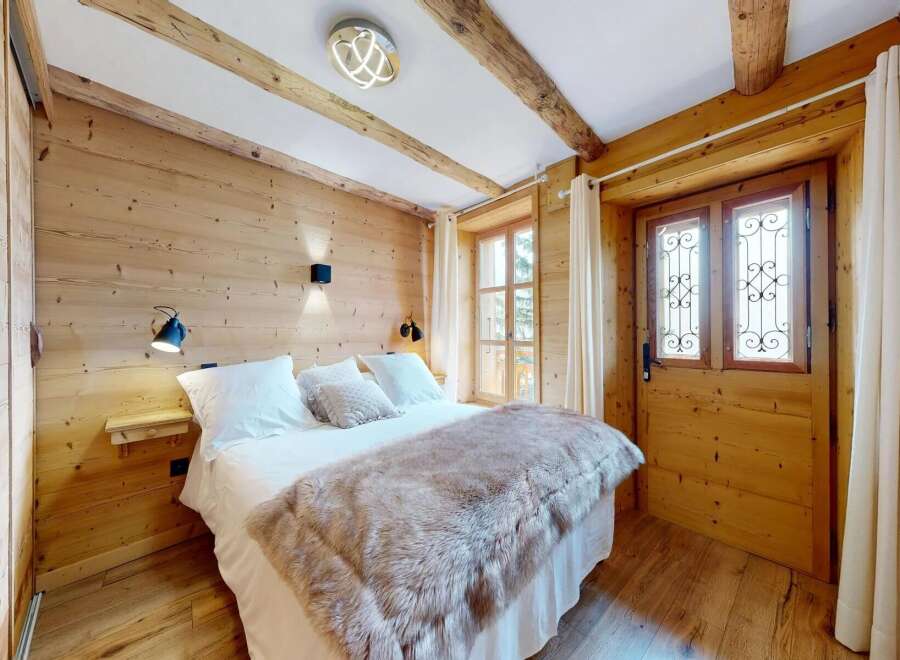 Experience rustic charm in this cozy bedroom featuring natural wood paneling and exposed beams.