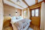 Experience rustic charm in this cozy bedroom featuring natural wood paneling and exposed beams.
