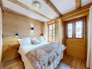 Experience rustic charm in this cozy bedroom featuring natural wood paneling and exposed beams.