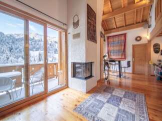 Experience the ultimate mountain retreat in this charming living space, featuring a cozy fireplace and stunning panoramic views of snow-covered peaks through expansive glass doors.