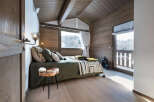 This cozy bedroom features a rustic design with wooden walls and a sloped ceiling, creating a warm and inviting atmosphere.