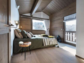 This cozy bedroom features a rustic design with wooden walls and a sloped ceiling, creating a warm and inviting atmosphere.