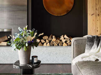 Experience luxury living in this stunning property, featuring a cozy living room with a fireplace and a stylish round mirror.