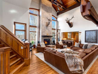 Step into luxury with this stunning property featuring a grand living room with a stone fireplace and soaring ceilings.