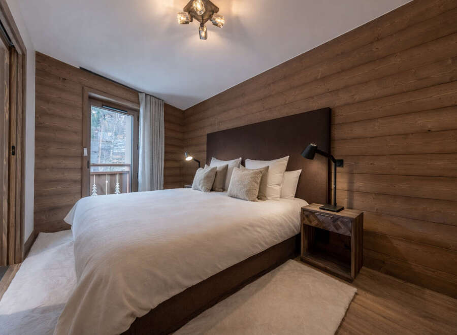 This stunning bedroom showcases a rustic design with wood-paneled walls and a cozy ambiance.
