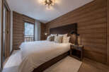 This stunning bedroom showcases a rustic design with wood-paneled walls and a cozy ambiance.