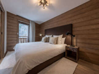 This stunning bedroom showcases a rustic design with wood-paneled walls and a cozy ambiance.