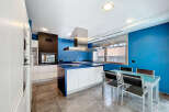 This modern kitchen boasts a sleek design with a striking blue accent wall and a spacious island.