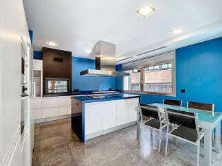 This modern kitchen boasts a sleek design with a striking blue accent wall and a spacious island.