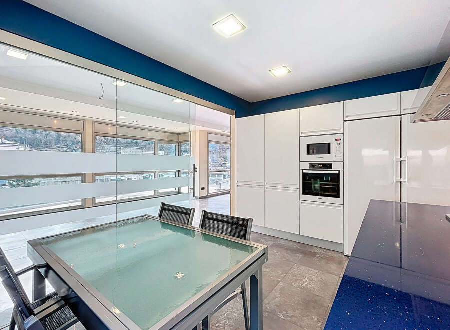 This modern kitchen boasts sleek white cabinetry and a striking blue countertop, creating a stylish and functional space.