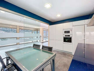 This modern kitchen boasts sleek white cabinetry and a striking blue countertop, creating a stylish and functional space.