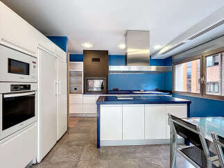 This modern kitchen boasts sleek white cabinetry and a striking blue accent wall, creating a stylish and inviting space.