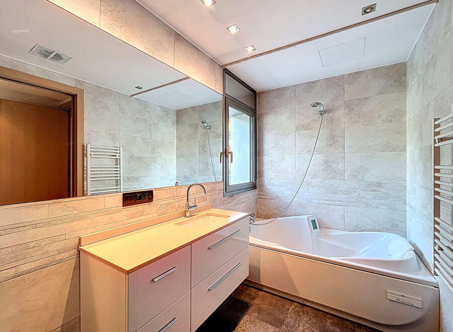 This modern bathroom boasts a sleek design with a spacious vanity and a luxurious bathtub.