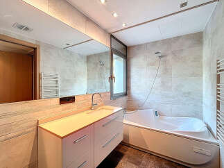This modern bathroom boasts a sleek design with a spacious vanity and a luxurious bathtub.
