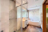 Step into luxury with this modern bathroom featuring a sleek glass shower enclosure and a relaxing bathtub.
