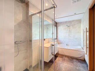 Step into luxury with this modern bathroom featuring a sleek glass shower enclosure and a relaxing bathtub.