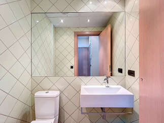 This modern bathroom features a sleek, minimalist design with a large mirror and a stylish sink.