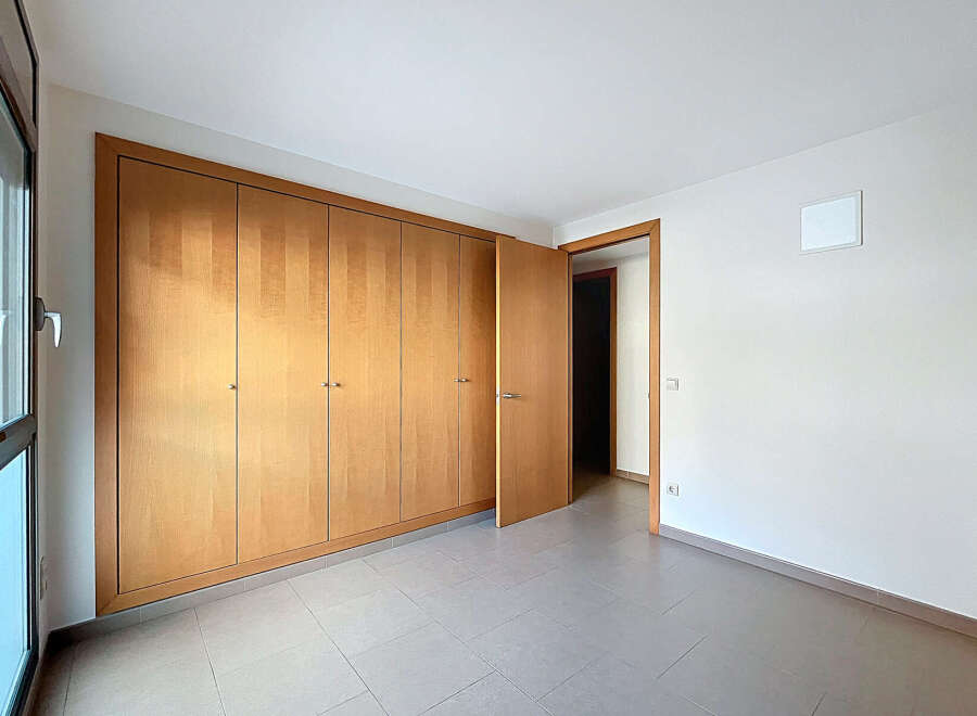 Discover the elegance of this well-lit room featuring a large wooden wardrobe, offering ample storage space.