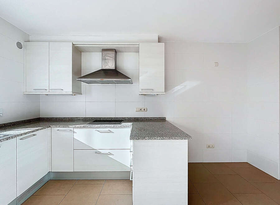This modern kitchen boasts sleek white cabinetry and a granite countertop, offering a clean and stylish aesthetic.