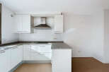 This modern kitchen boasts sleek white cabinetry and a granite countertop, offering a clean and stylish aesthetic.