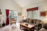 This cozy living room features a comfortable sofa, a charming wicker chair, and a beautiful view through the sliding glass door.