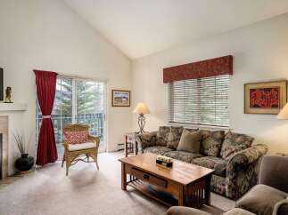 This cozy living room features a comfortable sofa, a charming wicker chair, and a beautiful view through the sliding glass door.