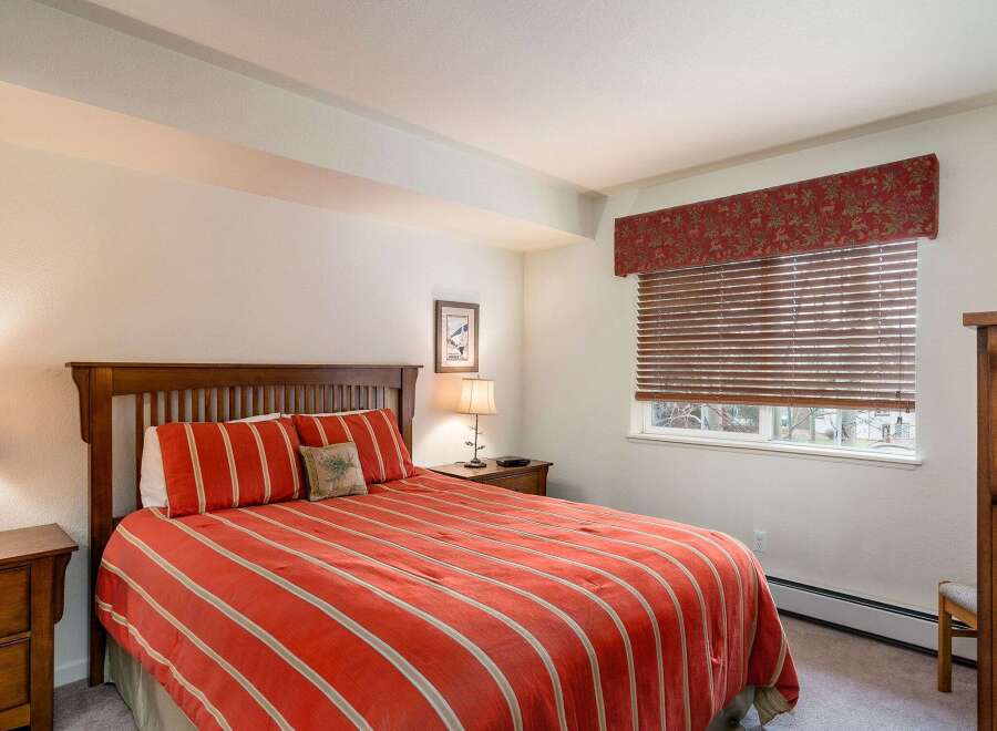 This cozy bedroom features a comfortable bed with a vibrant red and white striped comforter, creating a warm and inviting atmosphere.