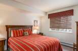 This cozy bedroom features a comfortable bed with a vibrant red and white striped comforter, creating a warm and inviting atmosphere.