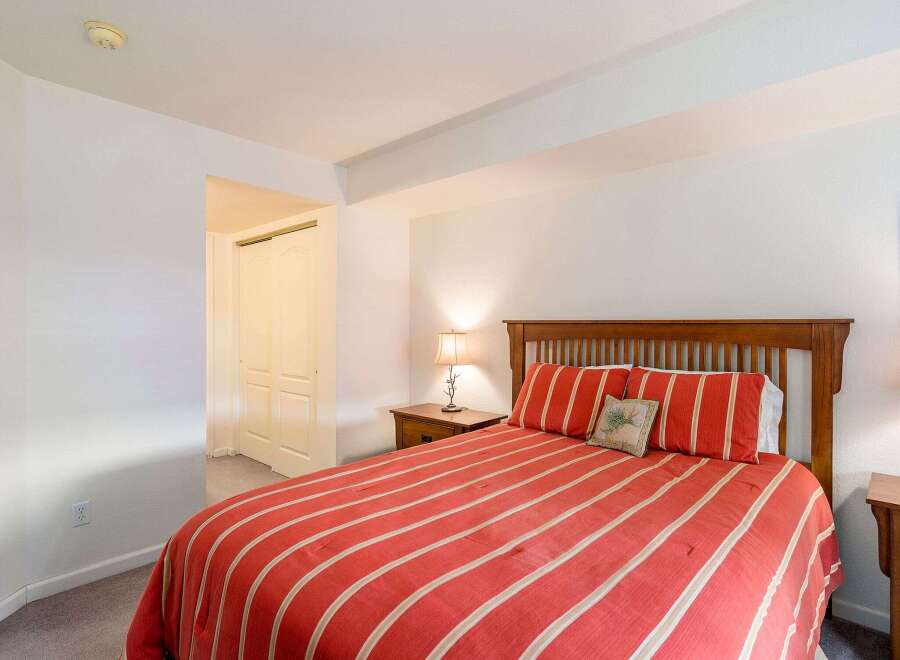 This cozy bedroom features a comfortable bed with a vibrant red and white striped comforter, creating a warm and inviting atmosphere.