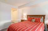 This cozy bedroom features a comfortable bed with a vibrant red and white striped comforter, creating a warm and inviting atmosphere.