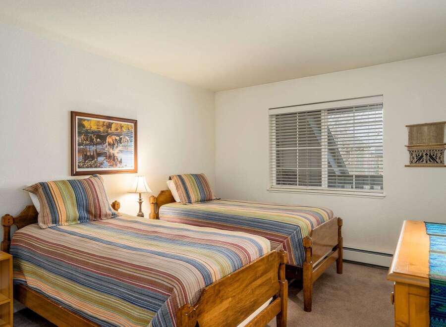 This cozy bedroom features two twin beds with colorful striped bedding, perfect for guests or a shared living space.