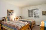 This cozy bedroom features two twin beds with colorful striped bedding, perfect for guests or a shared living space.