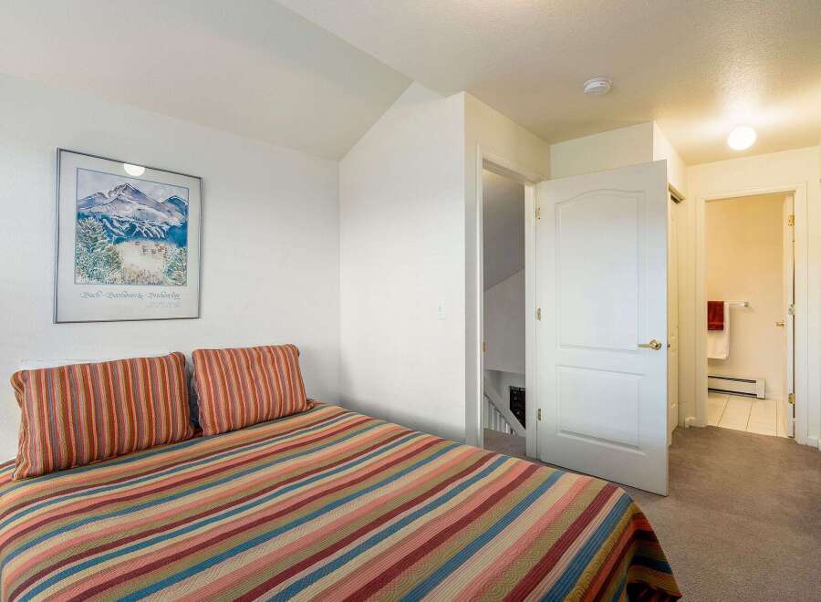 This cozy bedroom features a comfortable bed with colorful striped bedding and pillows, perfect for a relaxing retreat.