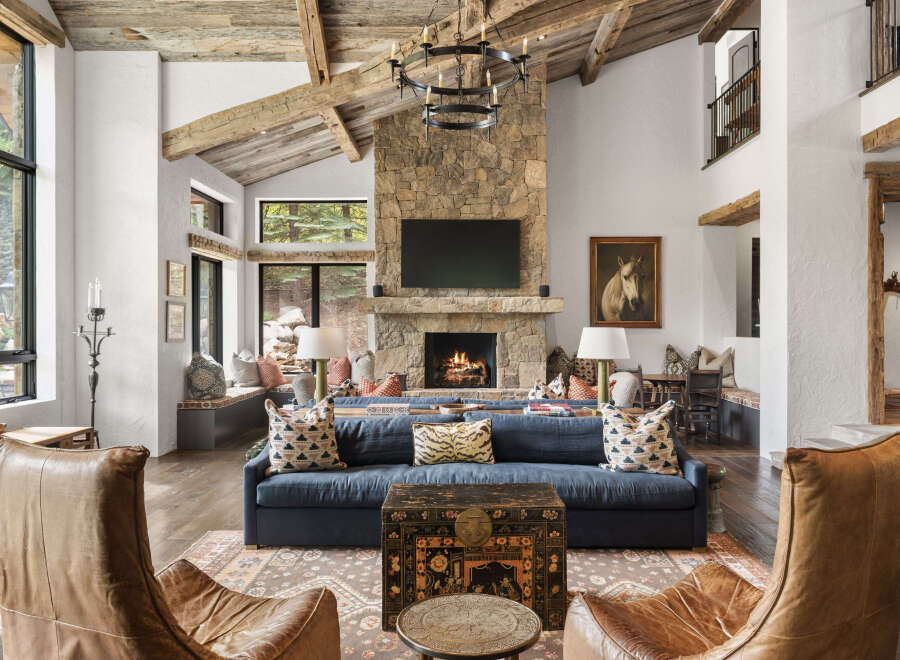 Experience luxury living in this stunning property, featuring a grand living room with a stone fireplace and exposed wooden beams.