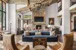 Experience luxury living in this stunning property, featuring a grand living room with a stone fireplace and exposed wooden beams.