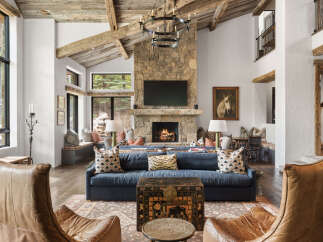 Experience luxury living in this stunning property, featuring a grand living room with a stone fireplace and exposed wooden beams.