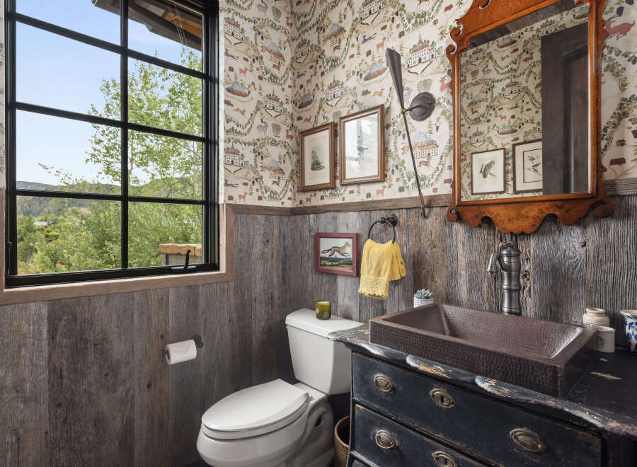 This charming bathroom features rustic wood paneling and a unique copper sink, creating a warm and inviting atmosphere.